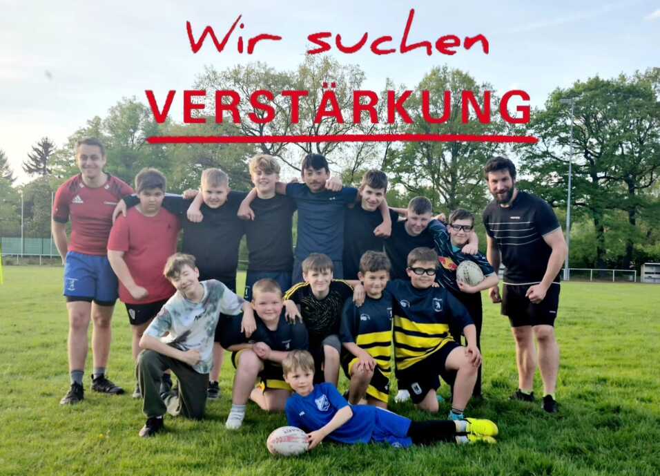 Kinderteam Gruppe von Kindern und Jugendlichen in Sportkleidung steht auf einem Rasen, ein Junge hält einen Rugbyball.