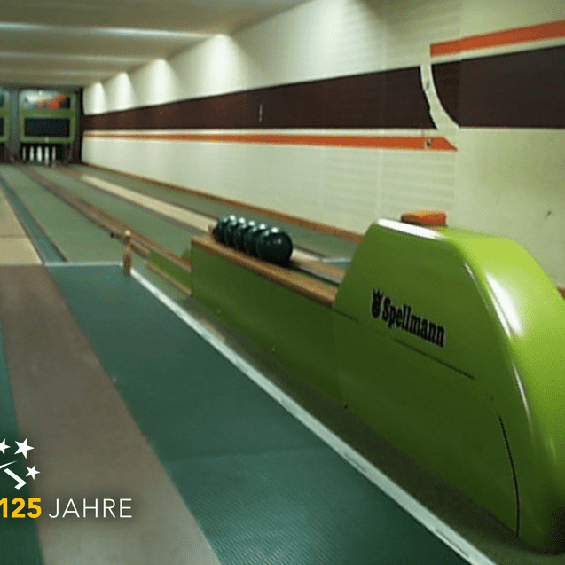 Blick auf eine Bowlingbahn mit grüner Bahn, einer Kegelbahn und Kegeln auf der rechten Seite.