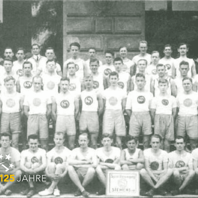 Schwarzweißfoto einer Sportmannschaft mit einheitlichen T-Shirts und Shorts,gestellt vor einer großen Tür.