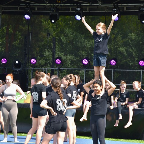 Gruppe von jungen M&auml;dchen w&auml;hrend einer Sportauff&uuml;hrung, eine steht auf den Schultern einer anderen.