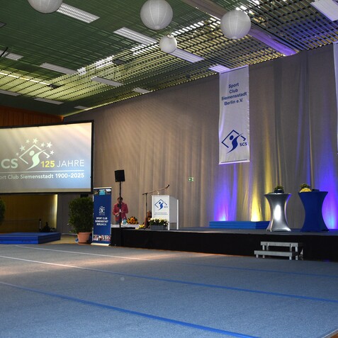 Festlich dekorierte Sporthalle f&uuml;r die Feier &bdquo;125 Jahre Sport Club Siemensstadt&ldquo; mit B&uuml;hne und kulinarischen Angeboten.