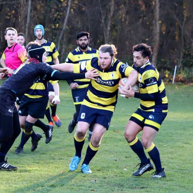 Rugby-Spieler im Wettkampf, einer zieht den Balltr&auml;ger, w&auml;hrend andere Spieler im Hintergrund agieren.