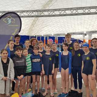 Gruppenshot von Schwimmern in Vereinskleidung vor einem Schwimmbecken, Banner im Hintergrund zeigt &bdquo;SCS Schwimmen, Berlin&ldquo;.
