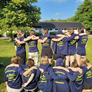 Gruppenaufnahme von Kindern in blauen T-Shirts mit &bdquo;SC Siemensstadt Berlin Wettkampfteam&ldquo; im Freien, umarmend.