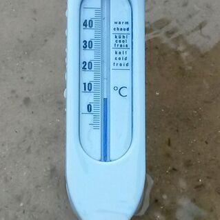 Thermometer in blauer Farbe zeigt Temperaturangaben in Celsius an, teilweise im Wasser liegend.