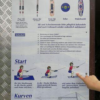 Hinweisschild zur Skiauswahl mit Sicherheitsanweisungen und Illustrationen zum Start sowie Kurven beim Wasserski.