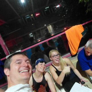 Gruppenbild von vier Personen am Schwimmbecken, lächelnd und entspannt, mit Schwimmausrüstung und Notizen.