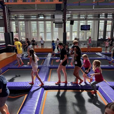 Szenen in einem Trampolinpark mit Kindern, die auf Trampolinen herumspringen und spielen. Helle und lebhafte Umgebung.