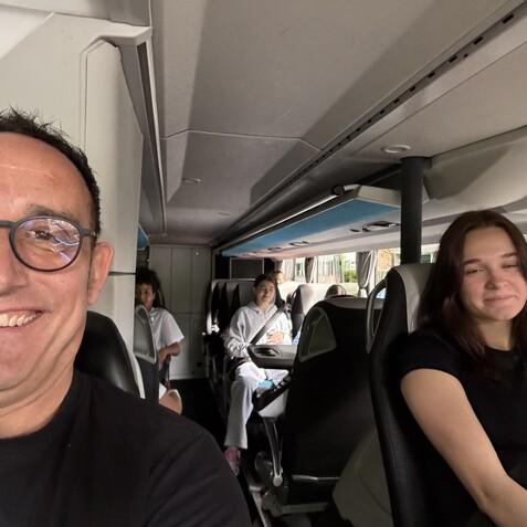 Selbstportr&auml;t eines Mannes im Bus, mit passagieren im Hintergrund, darunter eine l&auml;chelnde Frau.