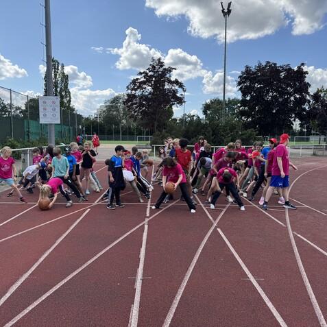 Gruppentraining von Kindern auf einer Bahn mit Sportger&auml;ten, w&auml;hrend sie sich auf das Training vorbereiten.