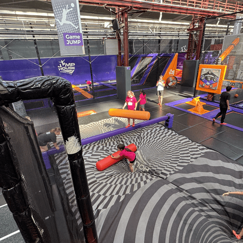 Trampolinpark mit mehreren Personen in Aktion, sowie speziellen Spielflächen und einer großen, gewellten Landefläche.
