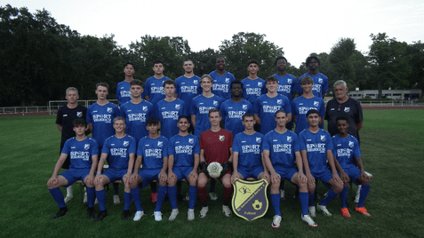 Mannschaftsfoto einer Fußballmannschaft in blauen Trikots auf einem Rasenplatz, umgeben von Bäumen.