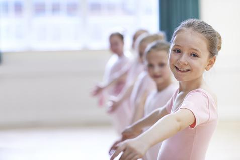 Gruppe junger Ballettt&auml;nzerinnen in rosa Kost&uuml;men, die sich l&auml;chelnd im Tanzsaal aufstellen.