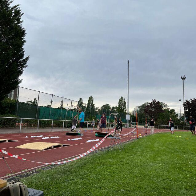 Sportveranstaltung auf einem Platz mit mehreren Personen, die an Übungen mit Hula-Hoops teilnehmen.