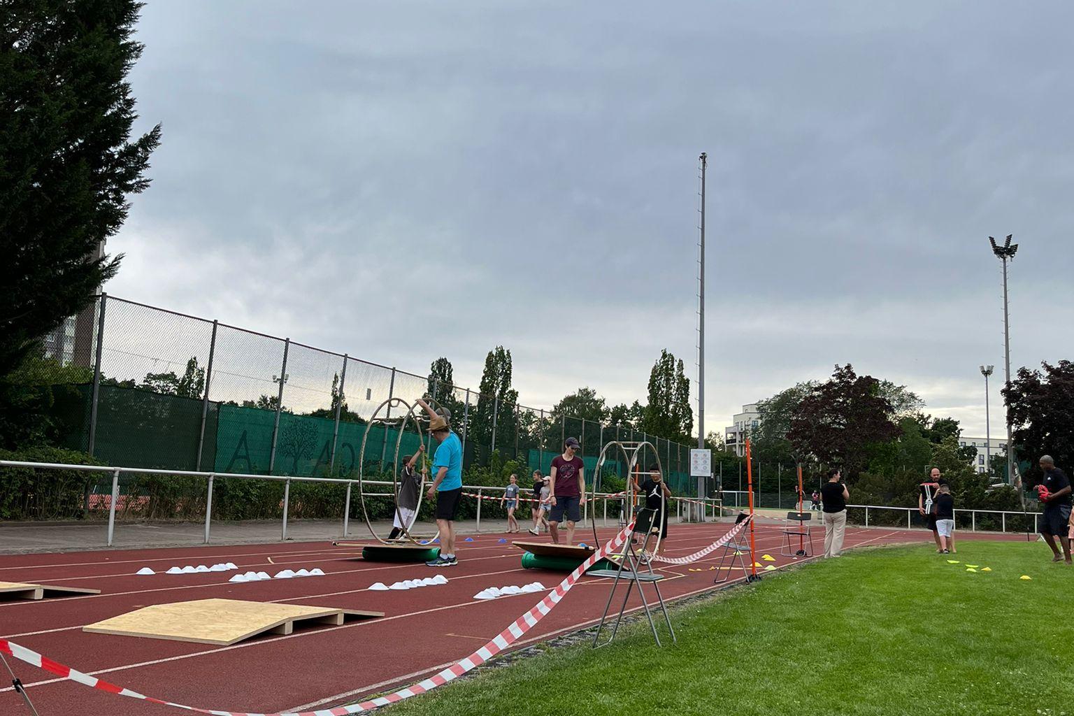 Sportveranstaltung auf einem Platz mit mehreren Personen, die an Übungen mit Hula-Hoops teilnehmen.