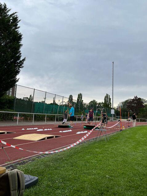 Sportveranstaltung auf einem Platz mit mehreren Personen, die an Übungen mit Hula-Hoops teilnehmen.