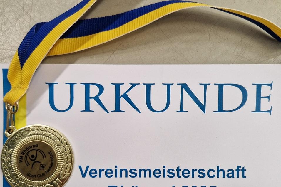 Goldmedaille mit blau-gelbem Band auf einer Urkunde f&uuml;r die Vereinsmeisterschaft im Rh&ouml;nrad 2025.
