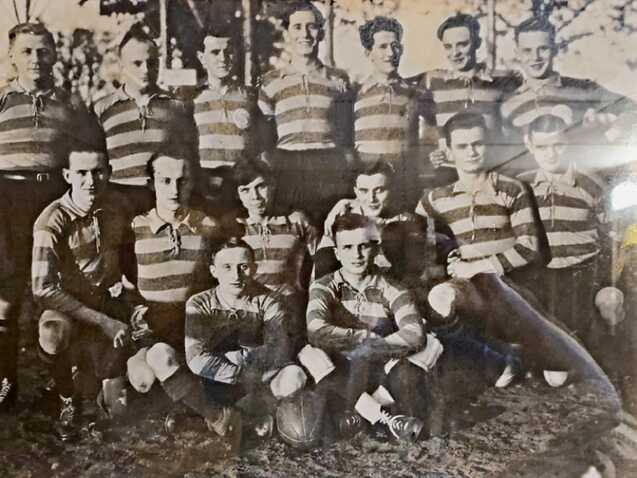 Gruppenfoto von 15 Spielern in gestreiften Trikots, die auf einem Fußballfeld posieren.