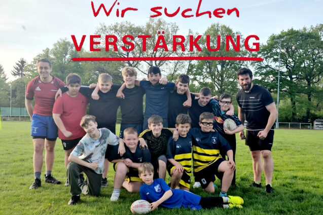 Kinderteam Gruppe von Kindern und Jugendlichen in Sportkleidung steht auf einem Rasen, ein Junge hält einen Rugbyball.