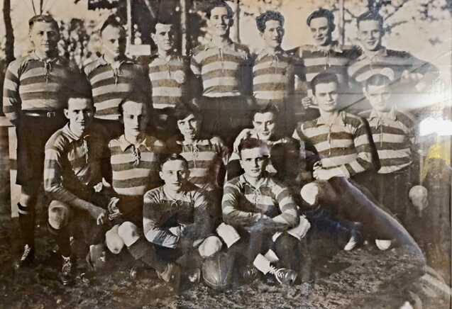 Gruppenfoto von 15 Spielern in gestreiften Trikots, die auf einem Fußballfeld posieren.