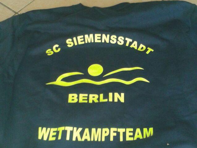 T-Shirt des SC Siemensstadt Berlin mit gelbem Schriftzug &bdquo;Wettkampfteam&ldquo; und schwimmendem Motiv.