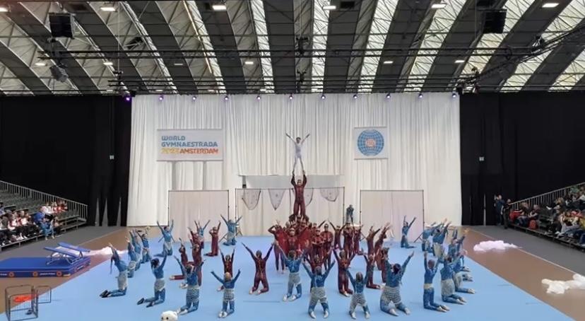Gruppenspieler in bunten Kost&uuml;men f&uuml;hren eine akrobatische Darbietung auf einer B&uuml;hne w&auml;hrend der World Gymnaestrada in Amsterdam vor.