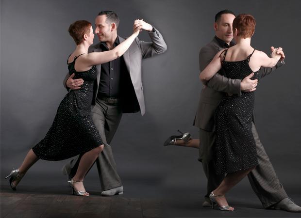 Tanzpaar in eleganter Kleidung tanzt eng umschlungen, auf grauem Hintergrund, ausdrucksvoll und harmonisch.