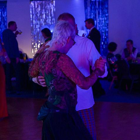 Tanzpaar in eleganter Abendkleidung bewegt sich auf einer festlich beleuchteten Tanzfläche.