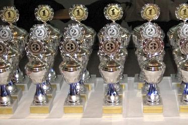 Reihe von silbernen Pokalen mit goldenen und silbernen Nummern 1 bis 3 auf einem wei&szlig;en Untergrund.