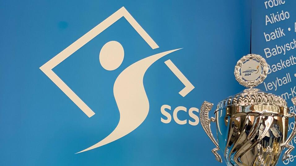 Vereinspokal des Sport Clubs Siemensstadt Berlin e.V. vor einer blauen Wand mit dem Vereinslogo und Text.