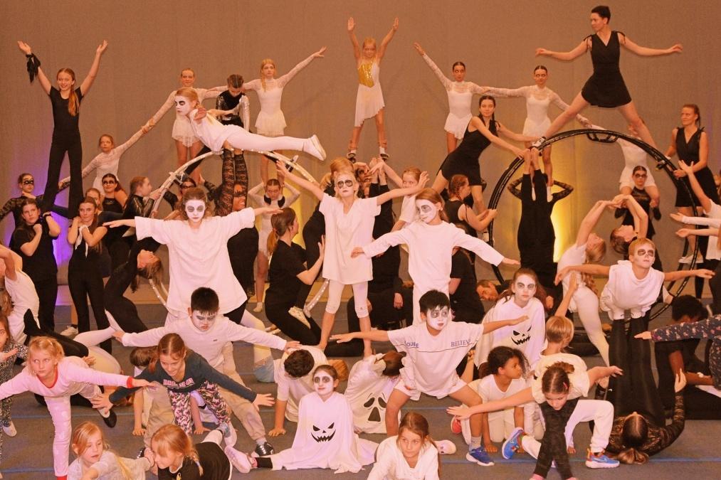 Gro&szlig;e Gruppe von Kindern und Jugendlichen in Kost&uuml;men mit Gesichtsbemalung, die an einer Tanzauff&uuml;hrung teilnehmen.