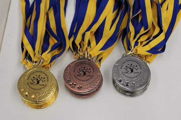 Drei Medaillen in Gold, Silber und Bronze mit blauen und gelben B&auml;ndern, beschriftet mit &bdquo;125 Jahre&ldquo;.