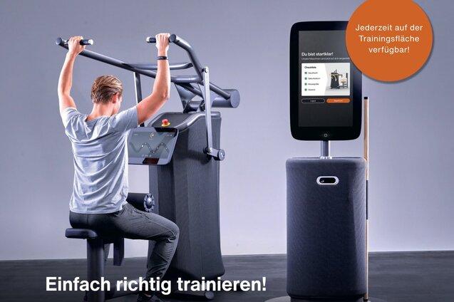 Mann trainiert an einem EGYM-Fitnessger&auml;t mit digitalem Monitor in modernem Fitnessstudio-Umfeld.