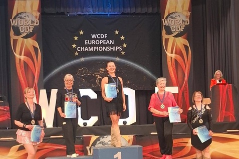 F&uuml;nf T&auml;nzerinnen stehen auf dem Siegertreppchen bei den WCDF European Championships, Urkunden in der Hand.