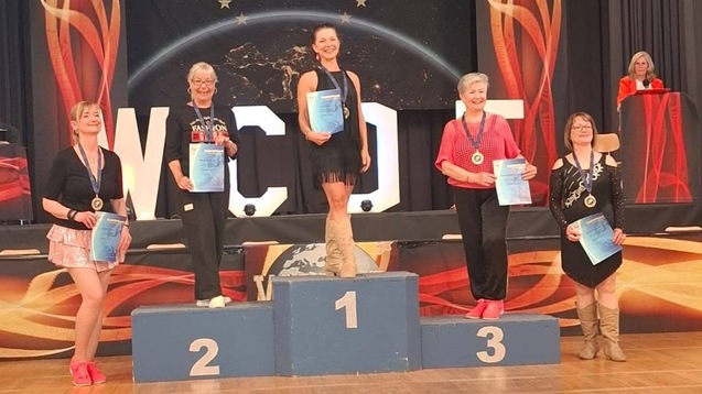 Fünf Tänzerinnen stehen auf dem Siegertreppchen bei den WCDF European Championships, Urkunden in der Hand.