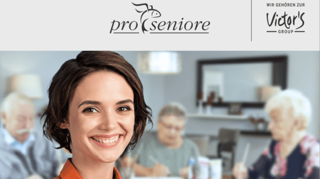 Lächelnde Frau mit kurzer Frisur trägt ein oranges Hemd, während im Hintergrund Senioren an einem Tisch aktiv sind.