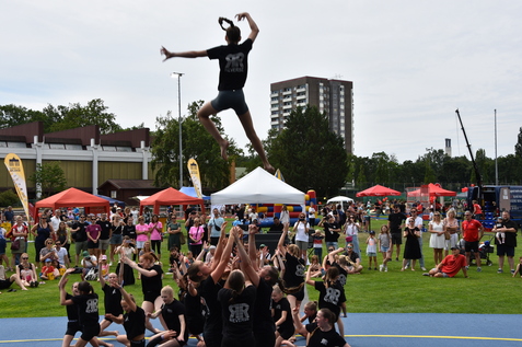 Sprung einer T&auml;nzerin von einer Menschentraube auf einer Freiluftveranstaltung mit Zuschauern.
