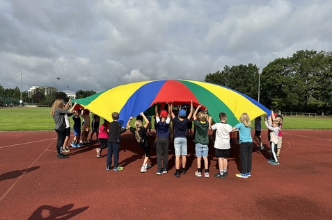 Kinder, die ein buntes Schwungtuch hochhalten