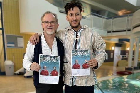 Zwei M&auml;nner stehen in einem Schwimmbad und halten Urkunden mit ihren Bildern in den H&auml;nden.
