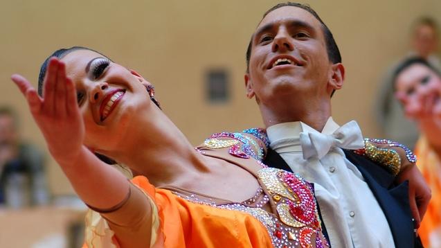 Tanzpaar in eleganter Kleidung zeigt einen Ausdruckstanz, die Frau in orange-weißer Robe, der Mann im Smoking.