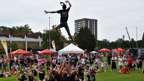 Sprung einer Tänzerin von einer Menschentraube auf einer Freiluftveranstaltung mit Zuschauern.