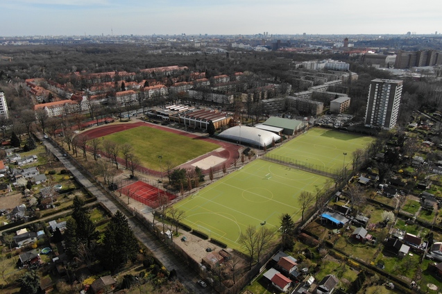 Luftaufnahme eines Sportgel&auml;ndes mit Tennispl&auml;tzen, Fu&szlig;ballfeld und Wohngeb&auml;uden in der Umgebung.
