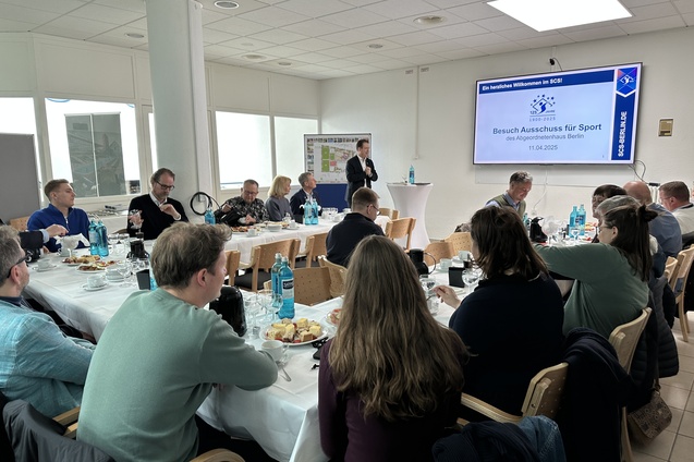 Gruppentreffen im SCSI mit Anwesenden am Tisch, Pr&auml;sentation im Hintergrund, Speisen und Getr&auml;nke auf dem Tisch.