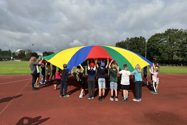 Kinder, die ein buntes Schwungtuch hochhalten