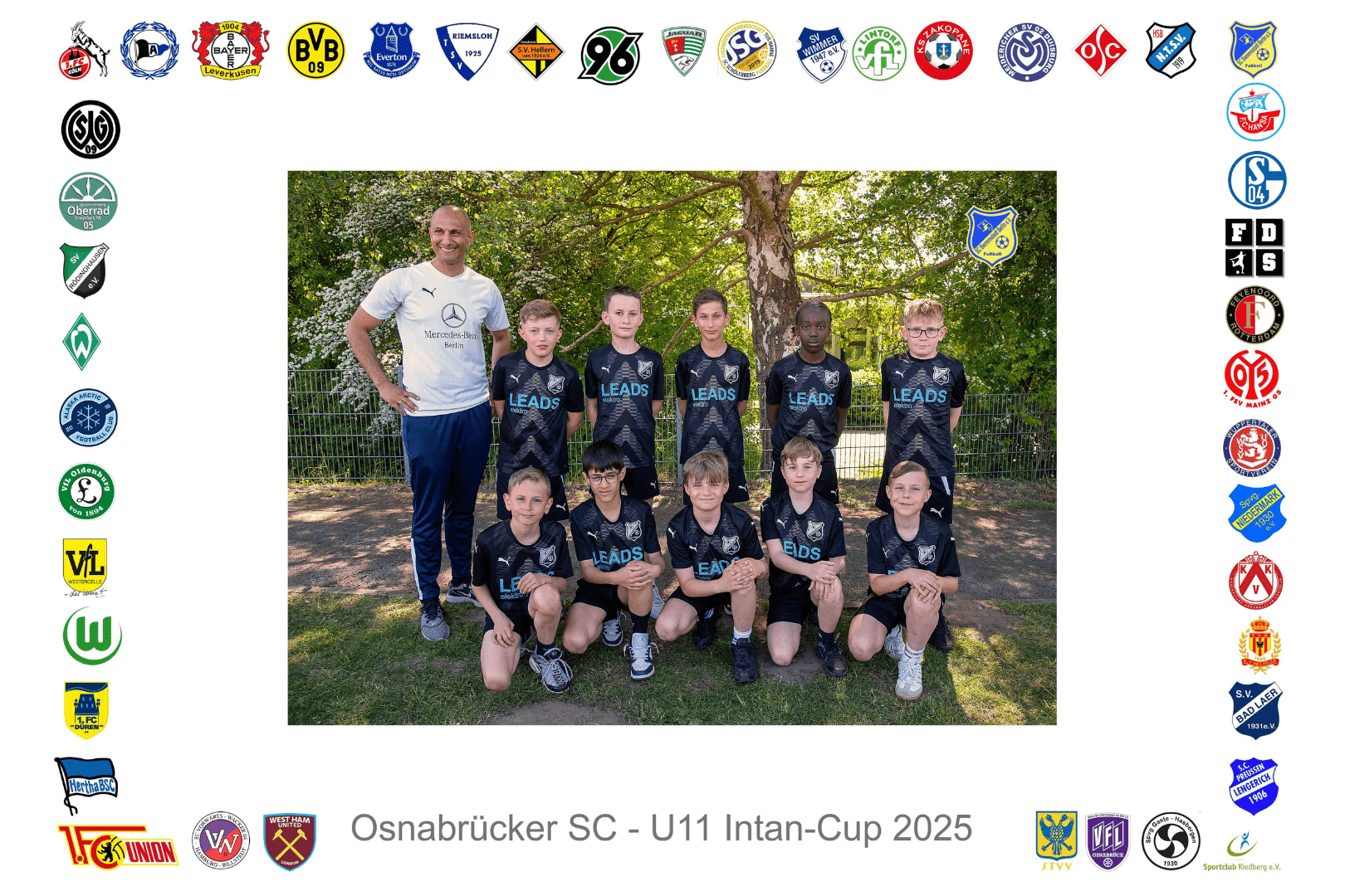 Gruppierung von zehn jungen Fu&szlig;ballspielern in schwarzer Teamkleidung, posierend mit Trainer in einem Park.