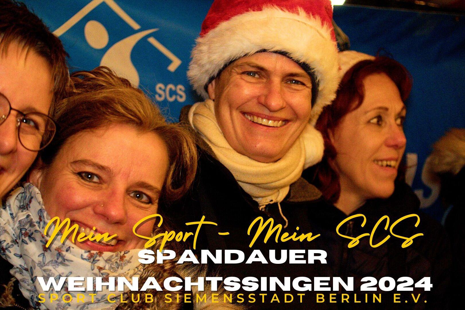 F&uuml;nf Frauen l&auml;cheln fr&ouml;hlich mit Weihnachtsm&uuml;tzen vor einem blauen Hintergrund beim Weihnachtssingen.