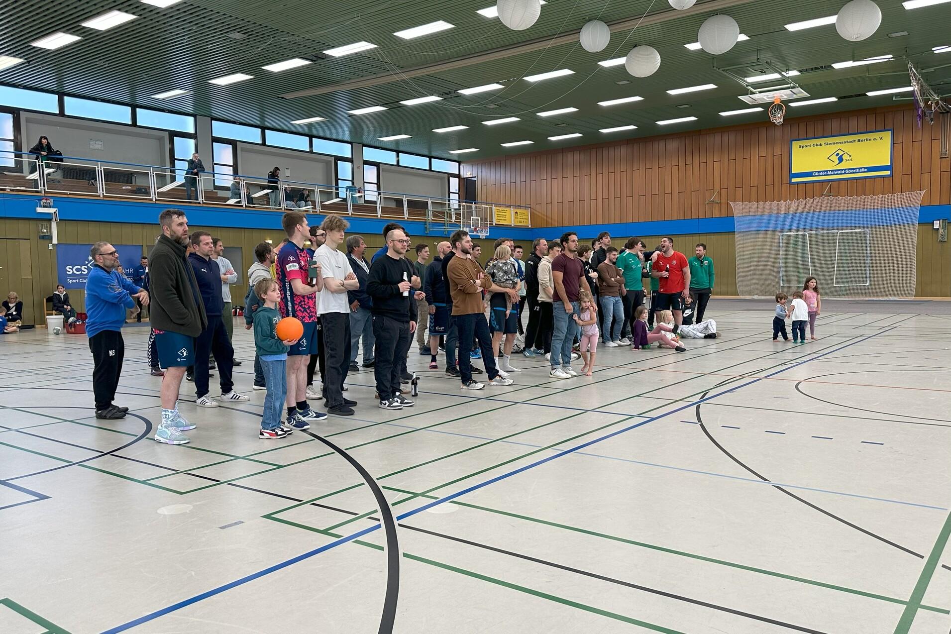Gruppe von Zuschauern in einer Sporthalle, einige Kinder halten einen Basketball, andere stehen in Warteschlange.