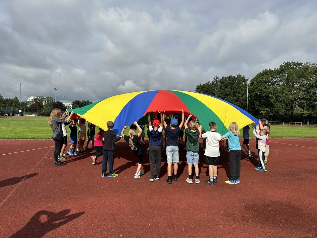 Kinder, die ein buntes Schwungtuch hochhalten