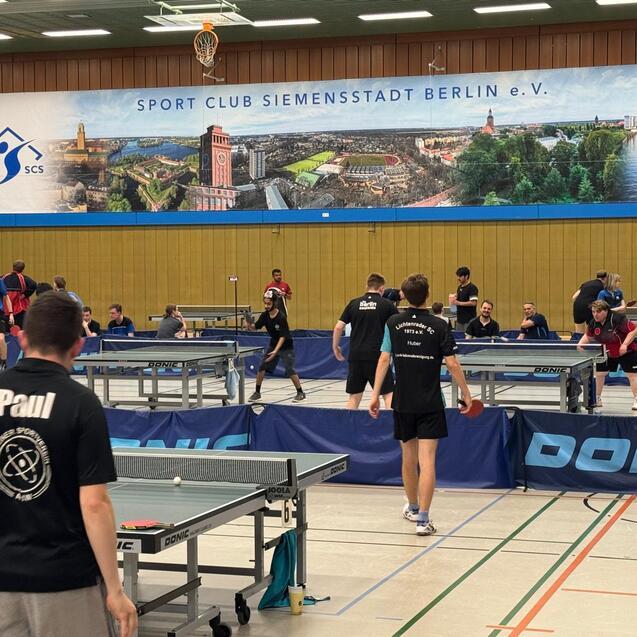Tischtennistraining mit mehreren Spielern an verschiedenen Tischen in einer Sporthalle des SC Siemensstadt in Berlin.