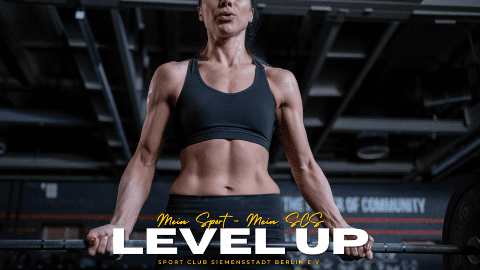 Nahaufnahme einer fitten Person, die an einer Stange im Fitnessstudio hängt, mit entblößtem Oberkörper und konzentriertem Ausdruck.